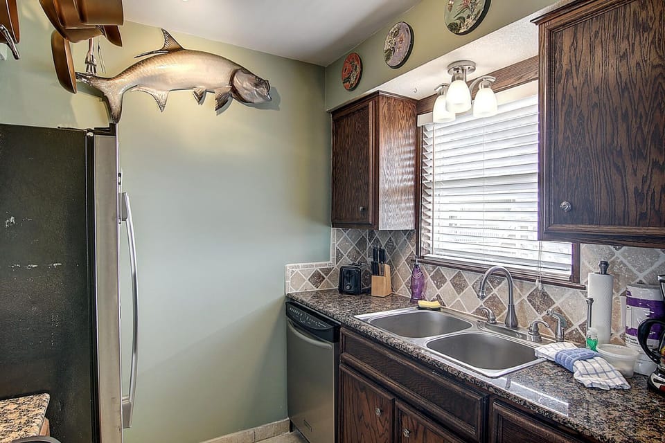 Prepare your fresh catch in this fully-equipped kitchen featuring granite countertops, rich wood cabinetry, and all the amenities needed for a memorable culinary experience.