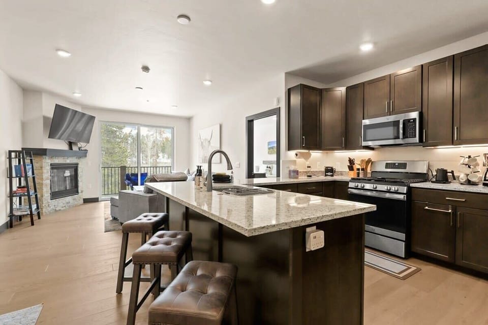 The stylish condo is a light-filled space with beautiful wood floors, an open layout, and views out toward the surrounding trees.
