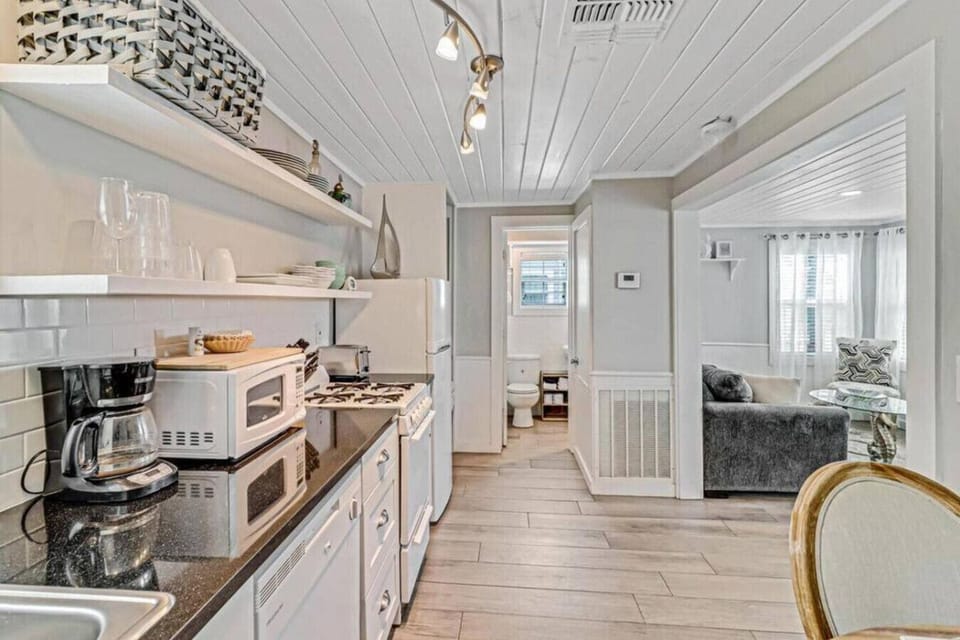 Kitchen with open shelving, full appliances, and bright natural light.