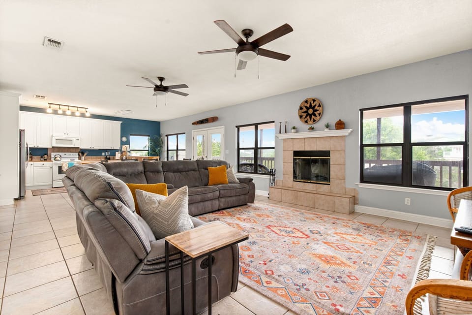 Main living room with lots of seating, reclining couch, wood burning fireplace