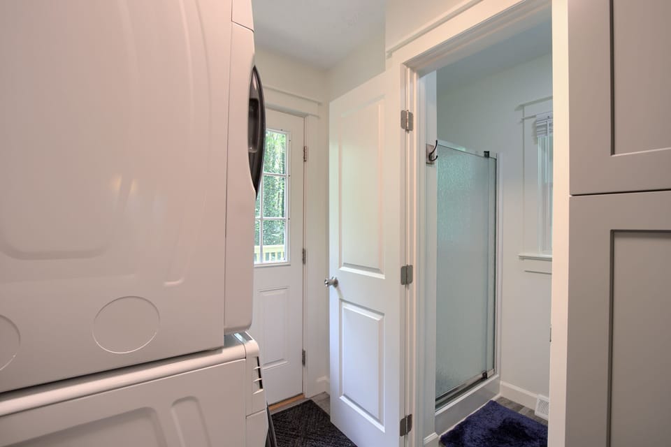 Laundry room with a peak into the small bathroom with glass shower door