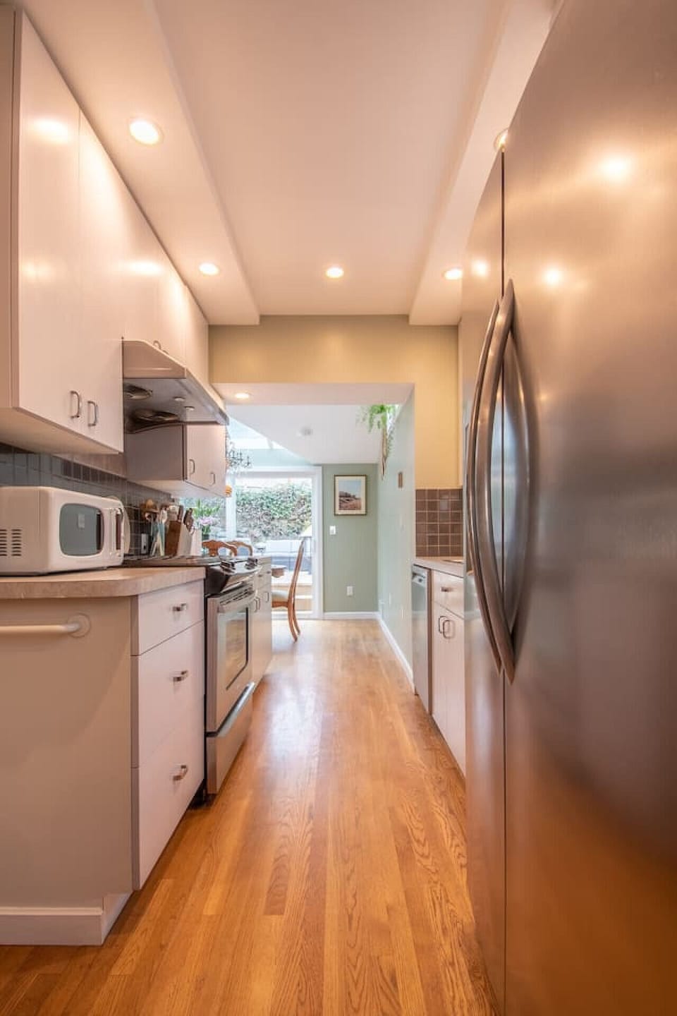 Another view of the the kitchen that is equipped all the essentials, stainless steel dishwasher, refrigerator, stove, and microwave.