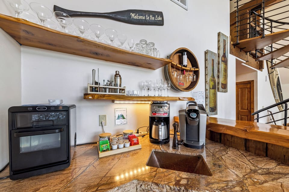 Coffee and beverage station with sink, mini fridge, glassware, and a convenient wet bar setup for guests