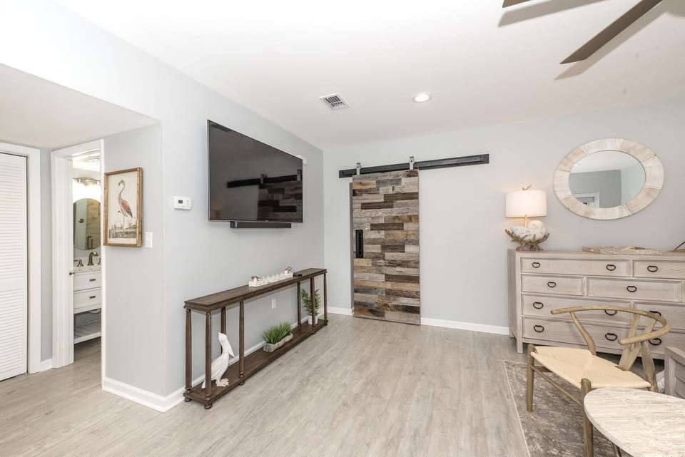 King-size bed, 75-inch smart TV, adjacent to pool-side balcony, with pool view