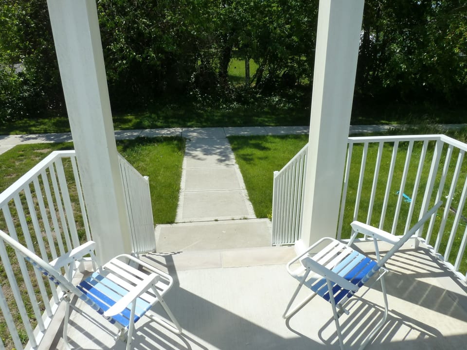 Covered porch overlooks small lawn and trees