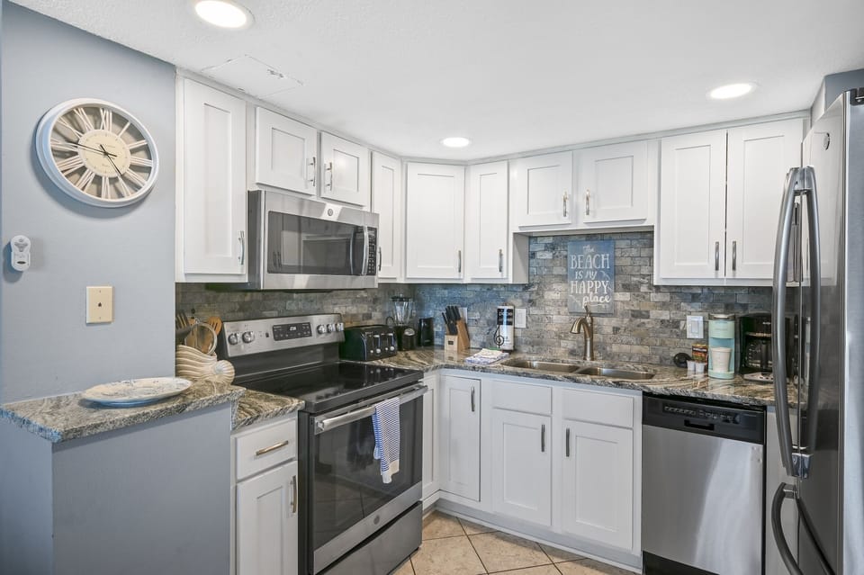 Your fully equipped kitchen features granite counters, stainless steel appliances, and coastal charm perfect for preparing memorable meals.