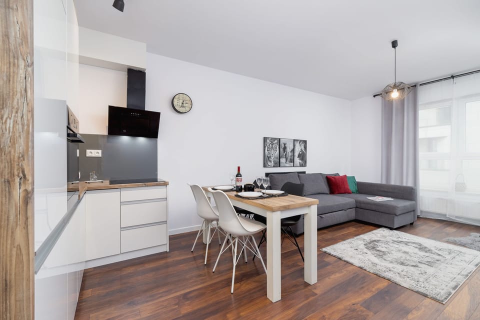 A sleek kitchen with modern appliances, including a built-in oven, microwave, and ample storage in white and black cabinetry. The kitchen opens up into the living and dining area.