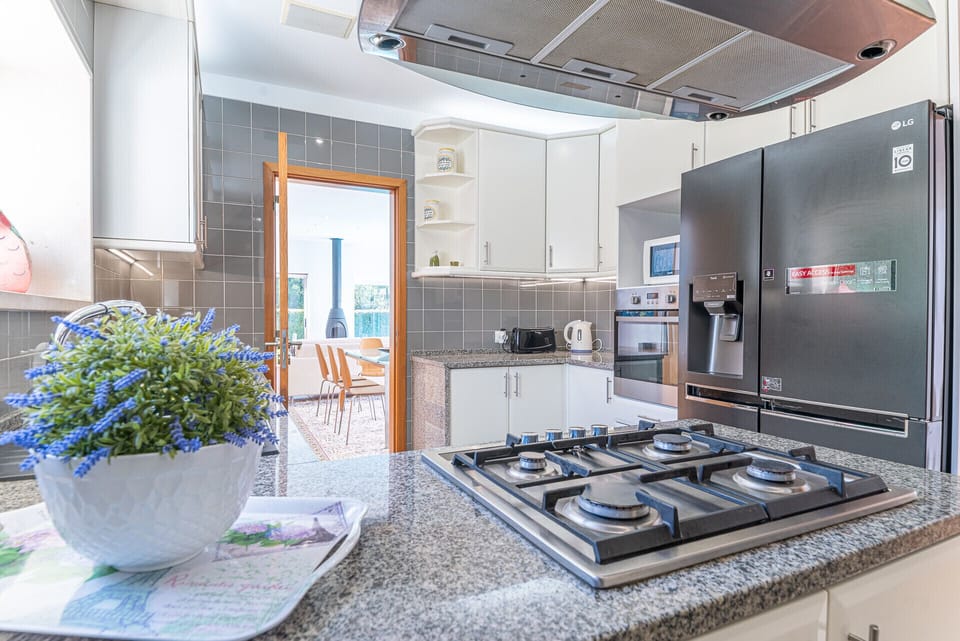 Modern kitchen with gas cooktop and stainless steel appliances — Villa Aroeira II, luxury holiday villa in Herdade de Aroeira