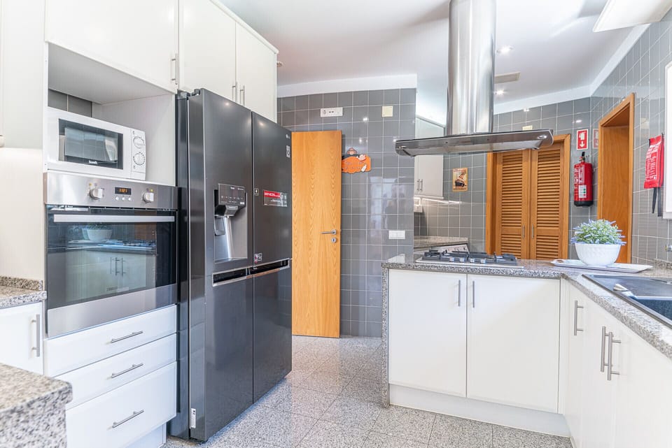 Modern kitchen with black appliances and granite countertops — Villa Aroeira II, holiday villa in Herdade de Aroeira