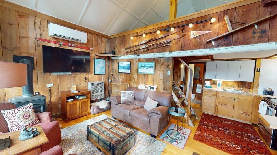 Open-concept cabin living space with comfy seating, TV, and rustic wood details.