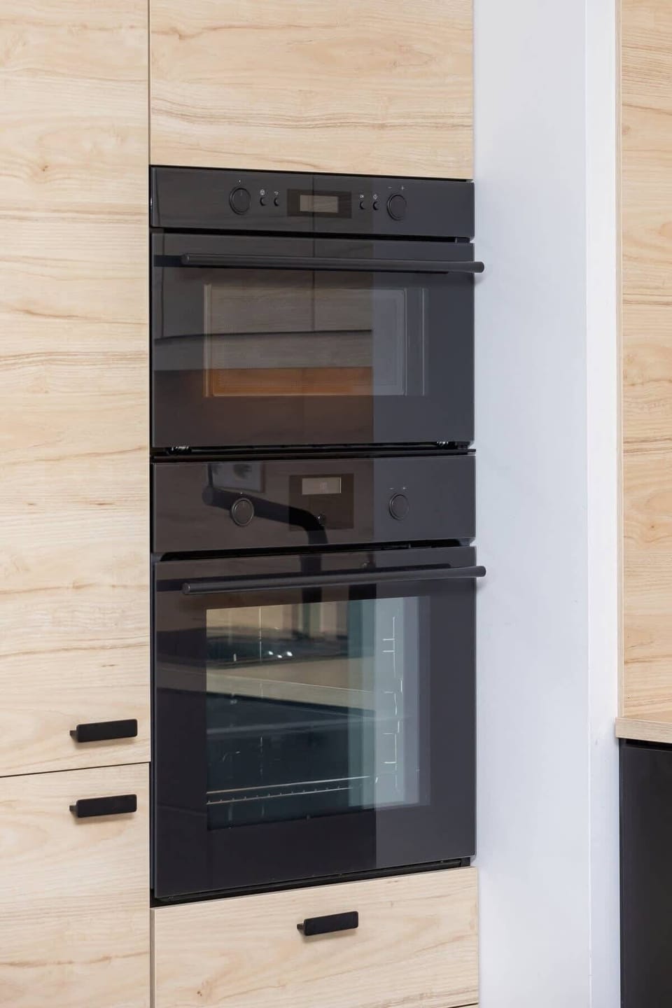 A fully equipped kitchen with built-in appliances and sleek black and wooden cabinetry.
