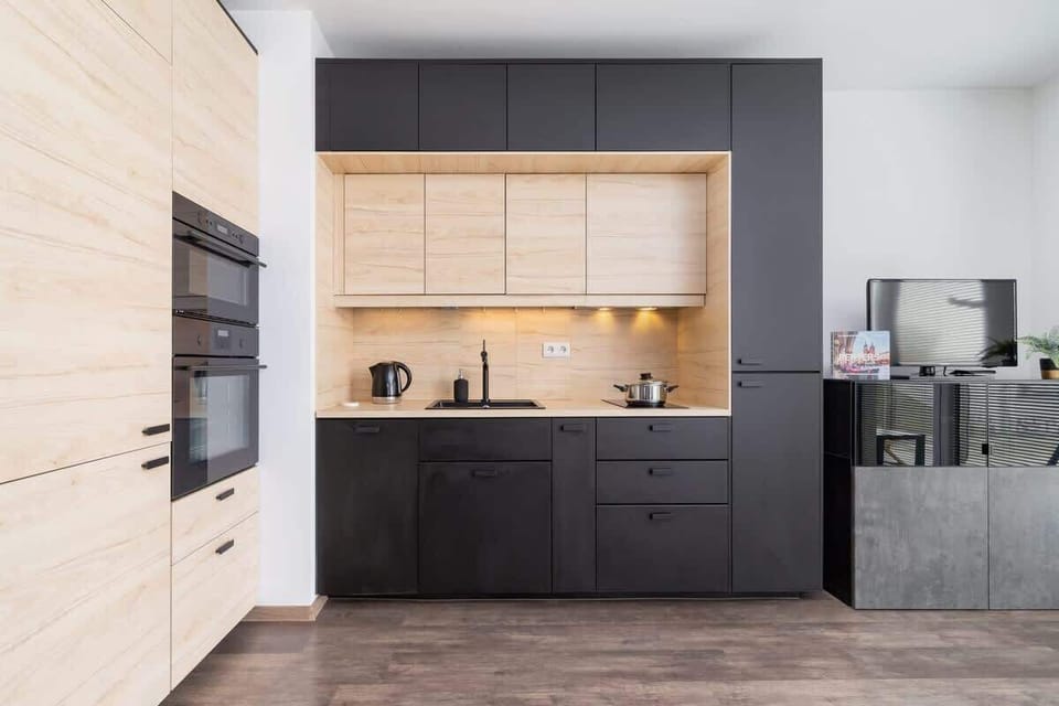A contemporary kitchen with contrasting wooden and black elements, complete with modern appliances.
