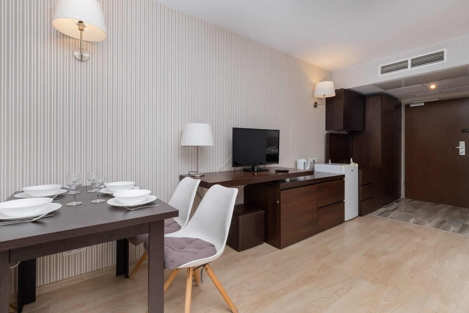 A dining area with a desk, lamp, and TV for added convenience.

