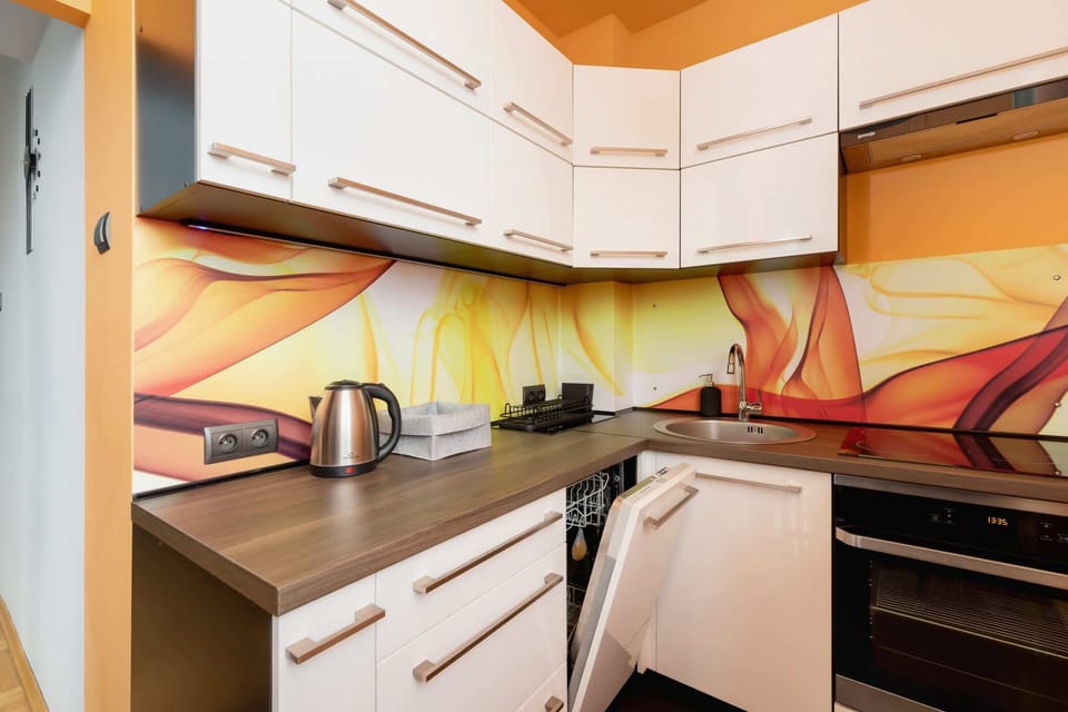 A compact kitchen with vibrant colors, wooden cabinetry, and modern appliances.
