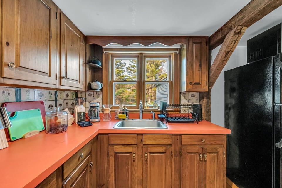The fully-equipped kitchen looks across a meadow.
