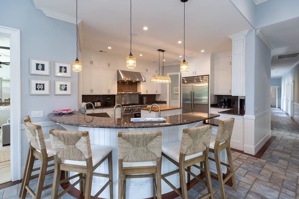 Spacious gourmet kitchen with granite countertops, custom white cabinetry, and a large island with bar seating—perfect for cooking and entertaining.