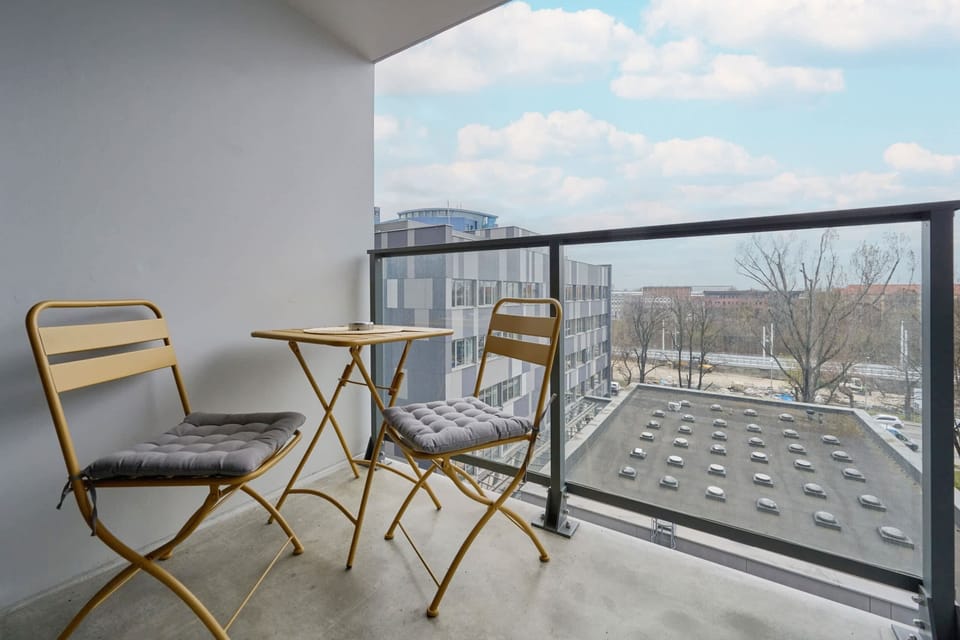 A balcony view featuring outdoor seating and a panoramic view of the urban landscape.
