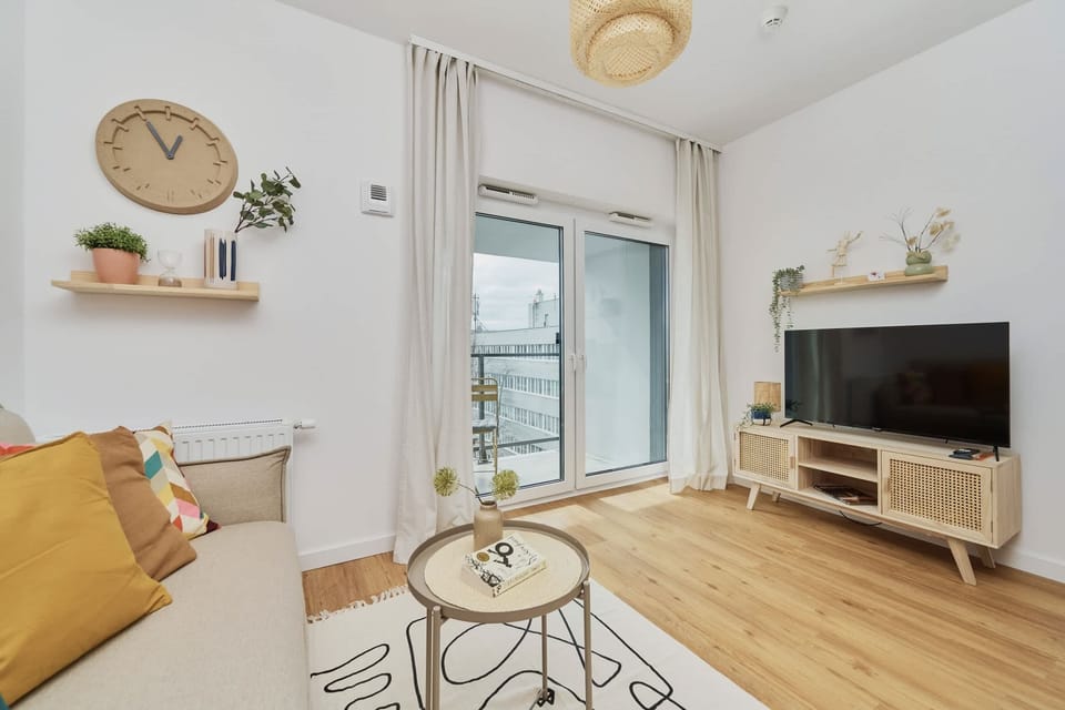 A well-lit living room with modern decor, shelves, and a TV unit for entertainment.
