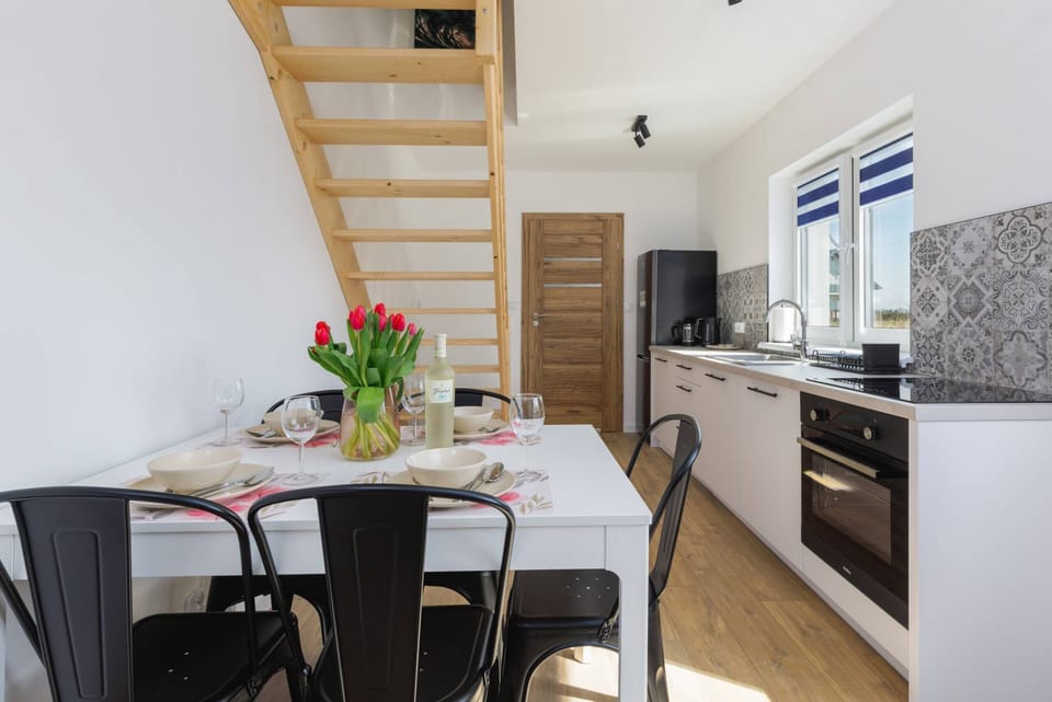 A compact yet fully equipped kitchen with white cabinetry and intricate patterned tiles on the backsplash. The space is designed for efficient meal preparation