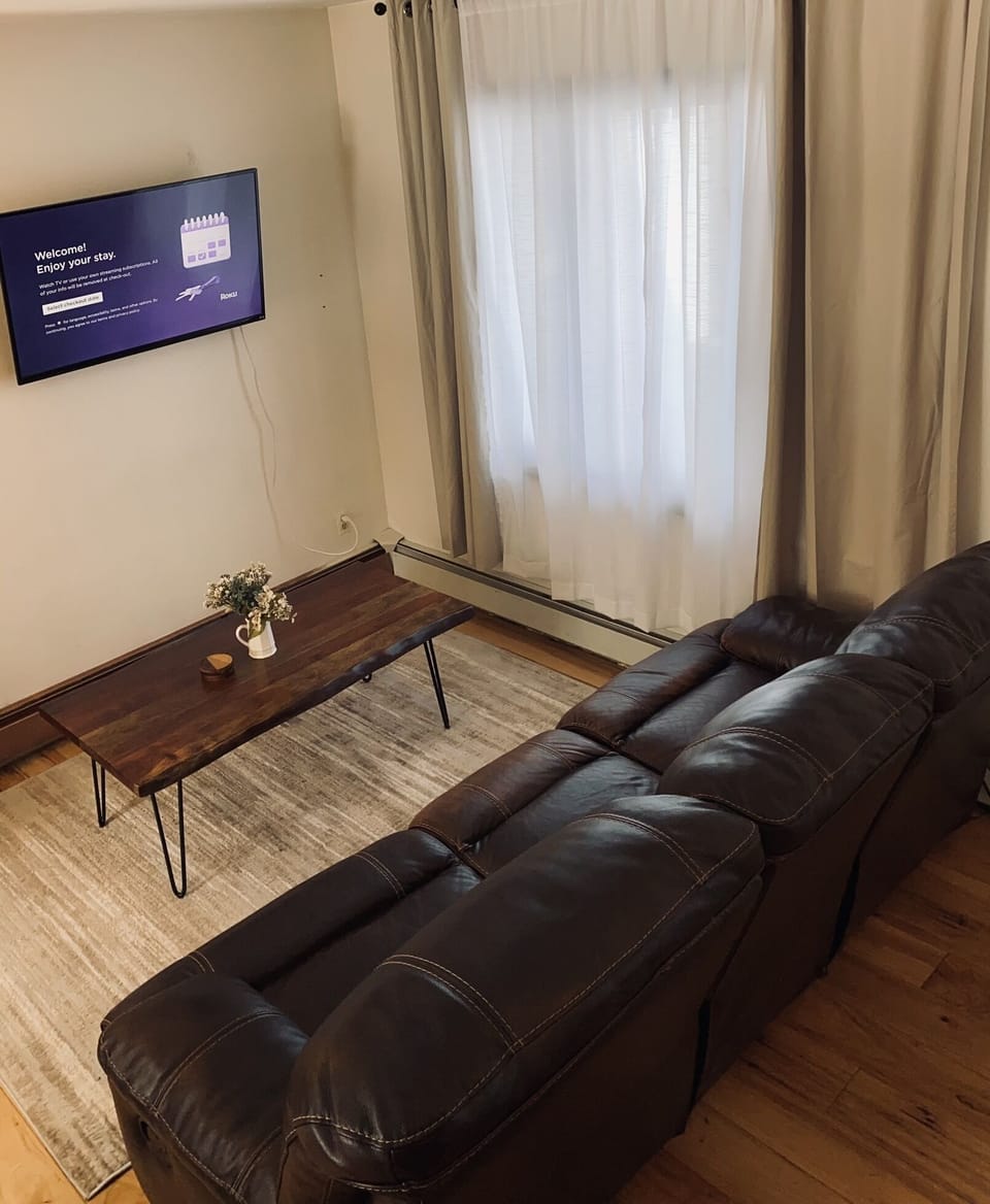 Roku TV with streaming platforms and a leather reclining couch. 