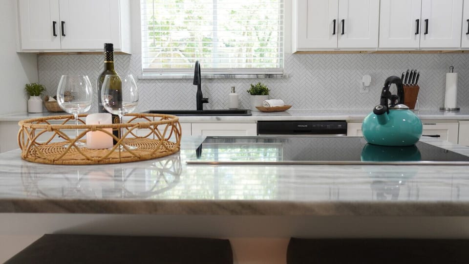 `Modern Elegance Meets Homely Warmth: Enjoy the best of both worlds in this stunning kitchen, where the glistening countertops and a bottle of wine await your arrival. Perfect for intimate dinners or a quiet night in. #ModernHome #CozyKitchen #WineLoversR