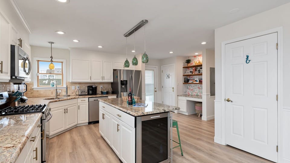 The wine fridge, dishwasher, refrigerator, and Desk can be seen in this photo