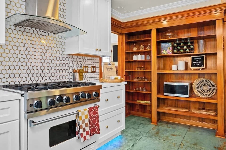 This thoughtfully designed kitchen showcases a premium gas range, classic tile backsplash, and stunning built-in wood shelving that blends style with functionality