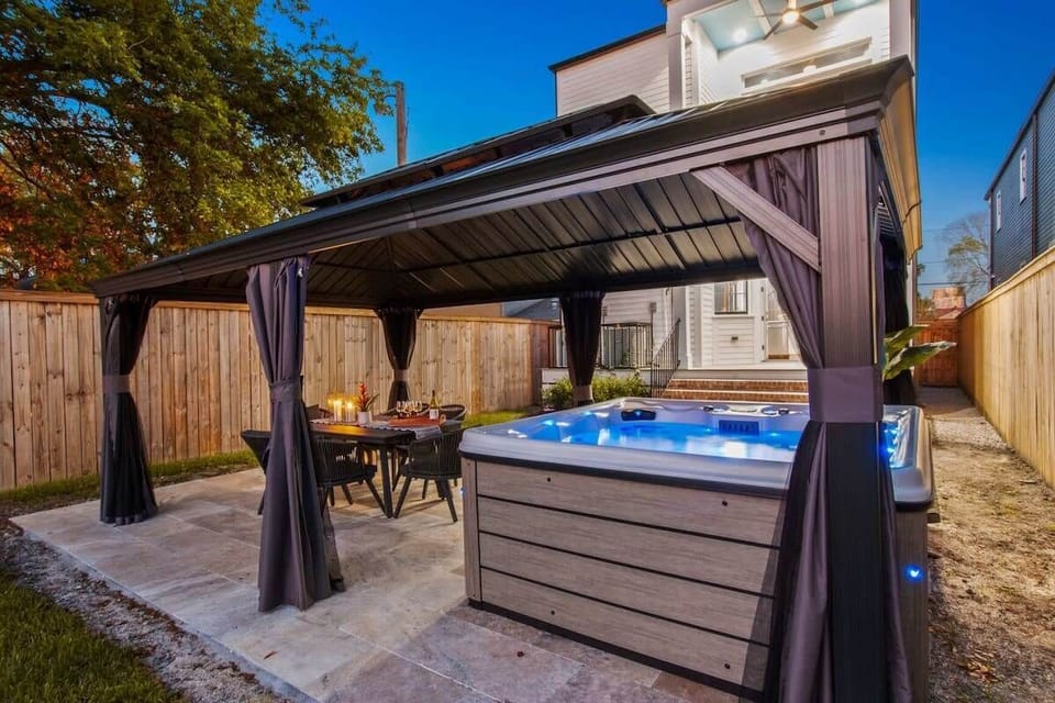 The outdoor space features a pergola, hot tub, and dining table