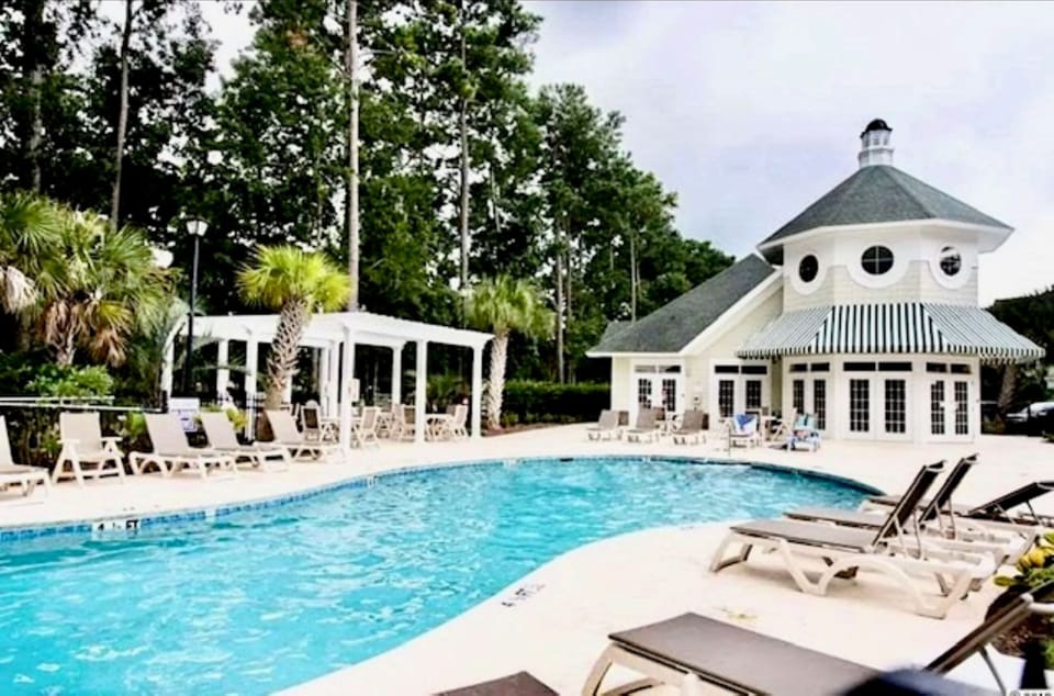 Relaxing poolside retreat with greenery & comfy loungers for the perfect escape.