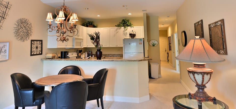 Open kitchen-dining with elegant lighting, modern decor & warm ambiance.