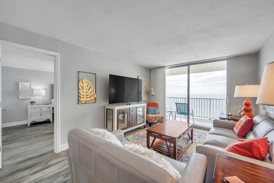 Bright living area w/ comfy seating, TV, & easy access to the balcony.