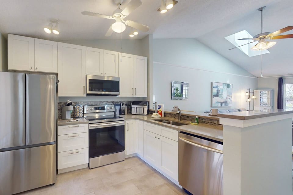 The modern kitchen is open to the living room and features quartz countertops and stainless steel appliances.
