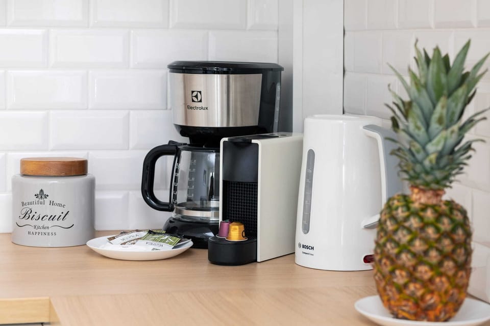 Well-equipped kitchen corner with a coffee maker, kettle, and a pineapple adding a welcoming touch.
