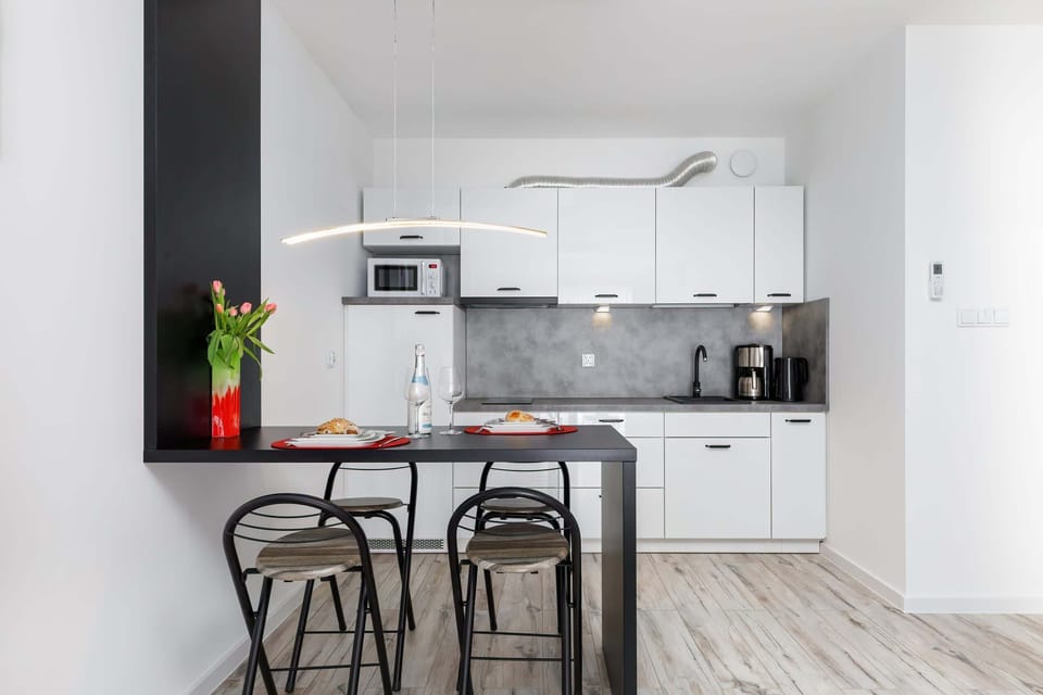 Functional kitchen with modern appliances, a small dining table, and fresh flowers for a homely feel.
