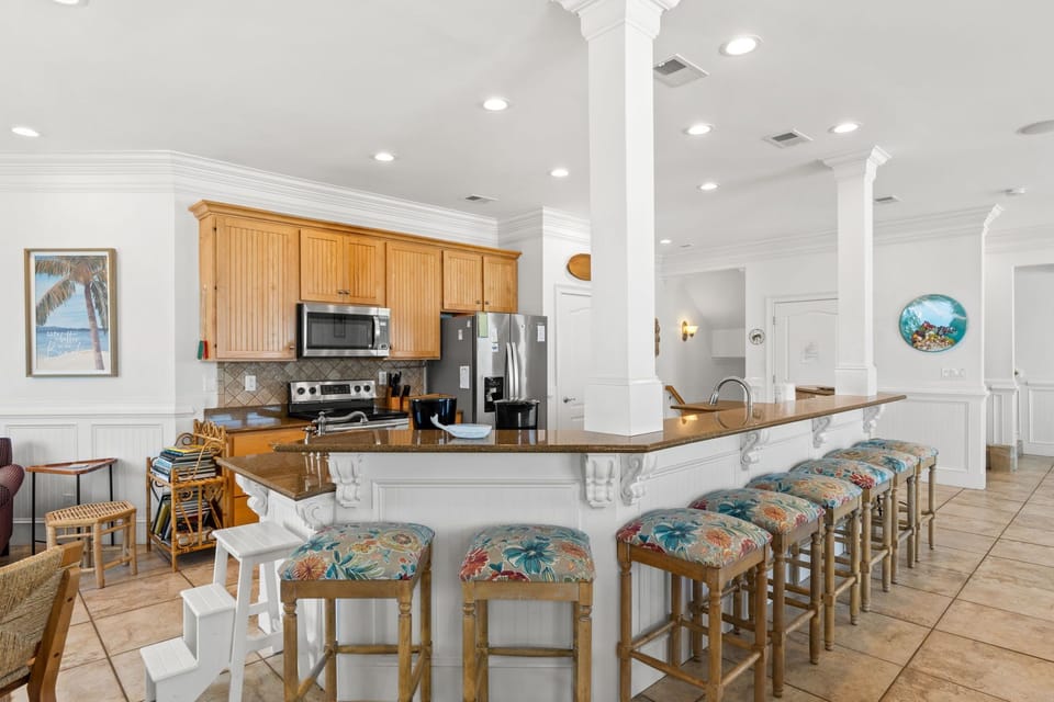 Gather around your spacious kitchen island with tropical-print seating, where morning coffee and evening conversations flow easily under bright, welcoming light.