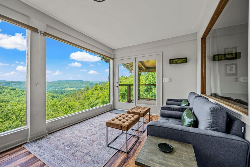 A sunroom with large picture windows framing natural beauty is the perfect spot for enjoying the first sip of morning coffee or melting into serene surroundings
