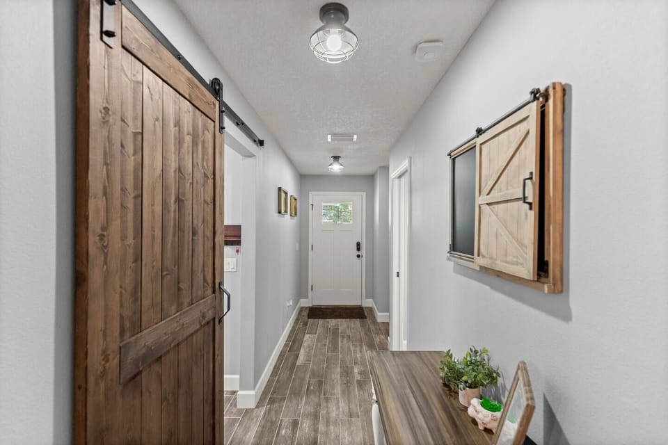 Welcoming hallway with rustic barn door charm — stylish touches and natural light set the tone