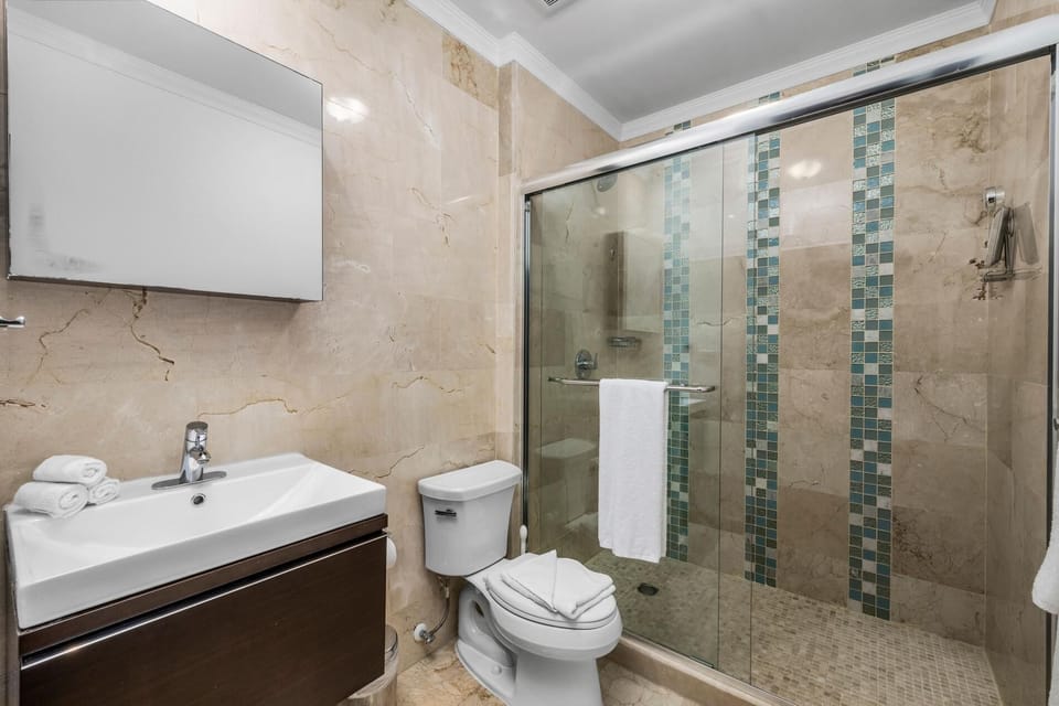 A full bathroom. Large mirror, unique bathroom sink with glass partition and toilet.