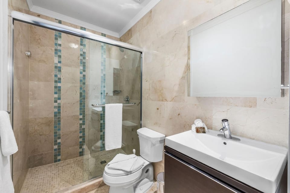 A full bathroom. Large mirror, unique bathroom sink with glass partition and toilet.