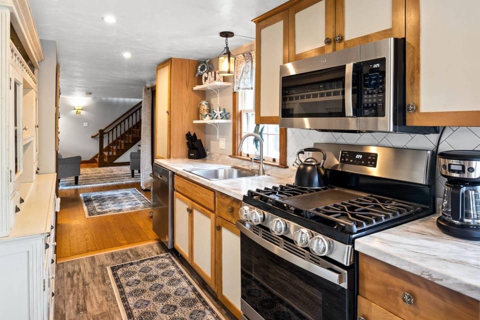 Modern kitchen with stove, oven, microwave, tea kettle, coffee maker, and dishwasher