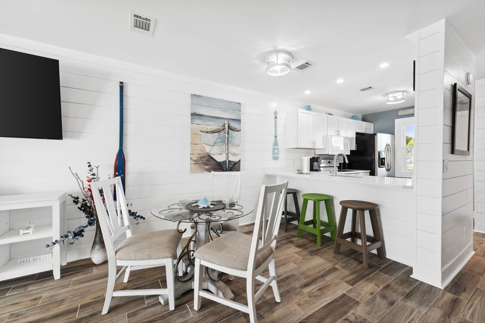bright coastal dining area with glass table and bar seating in a modern kitchen