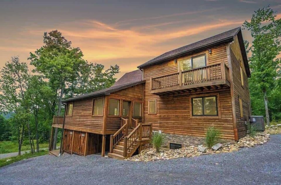 Dusk photo of the exterior.  The grave driveway is now paved with ample parking