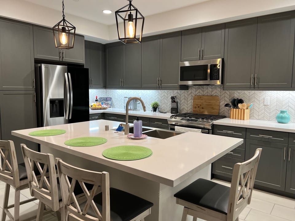 Kitchen with 4 chairs by island and 6 more chairs at dining table
