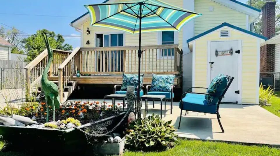 The back yard is large and sunny, with deck, patio, and a gas grill.