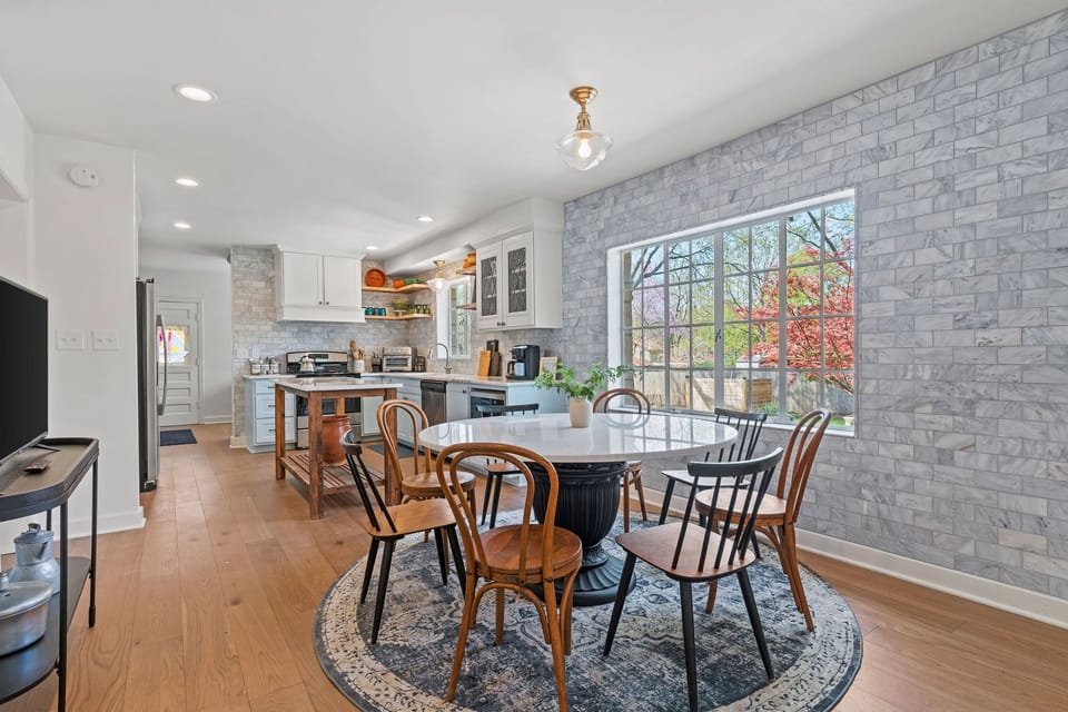 Spacious dining area with a round table, stylish seating, and natural light, seamlessly connected to the full kitchen. A Smart TV nearby makes it easy to enjoy meals, games, or casual gatherings.