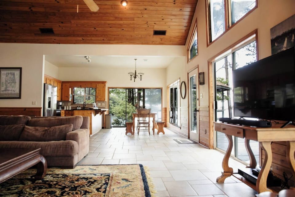 Open concept living room with large stone wood burning fireplace, Roku TV with sound bar, cable, and sports package.