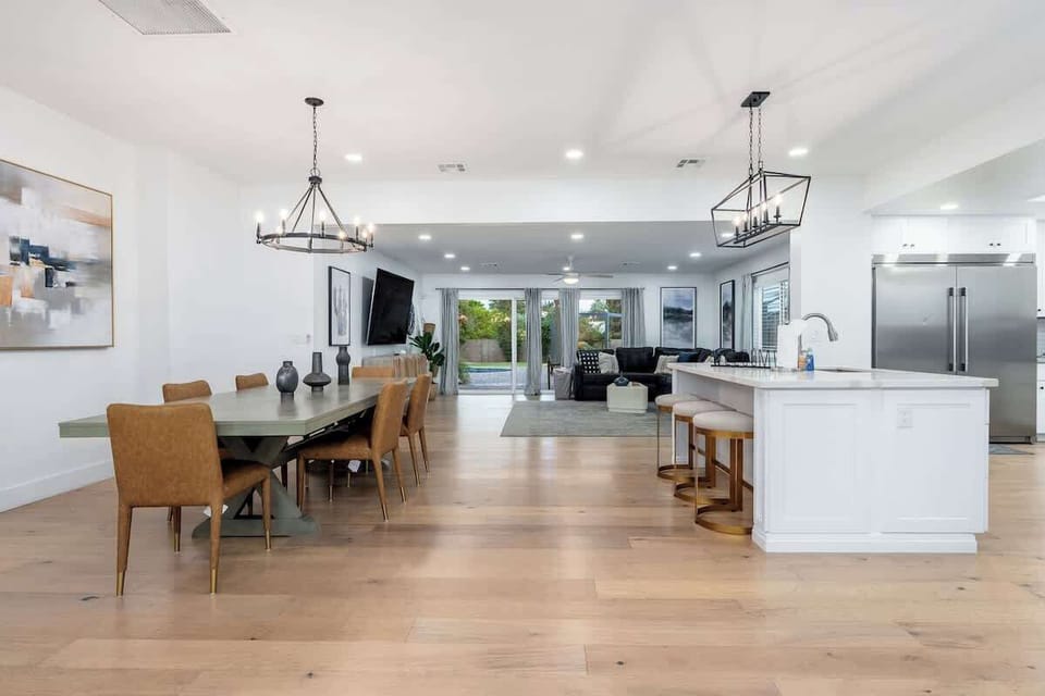 Relax in this spacious, sunlit great room where dining, lounging, and cooking flow seamlessly together—your perfect gathering space with warm wood floors and modern touches.