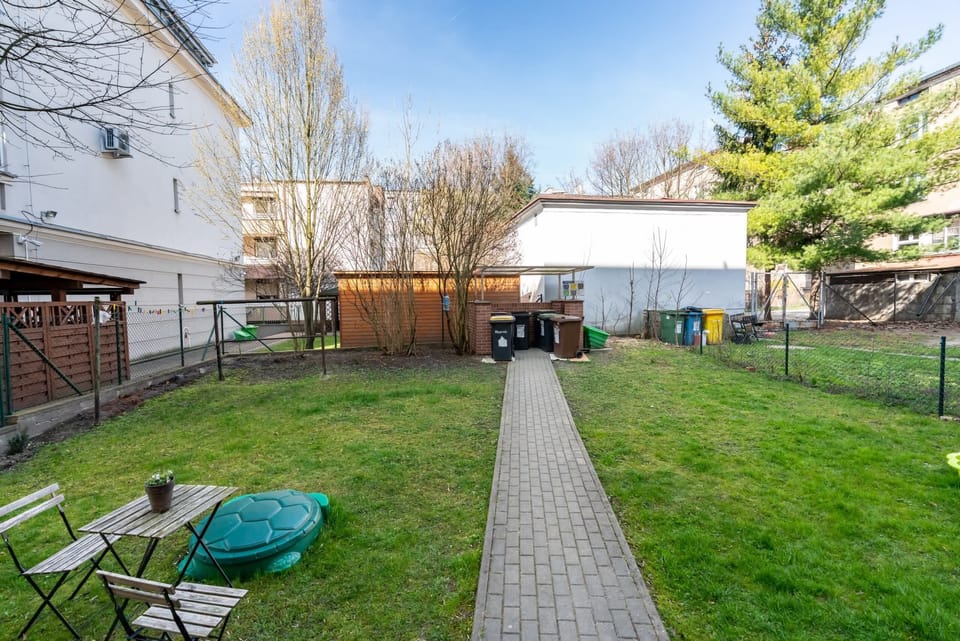 A shared outdoor space with green grass, pathways, and trees, located at the back of the apartment building.