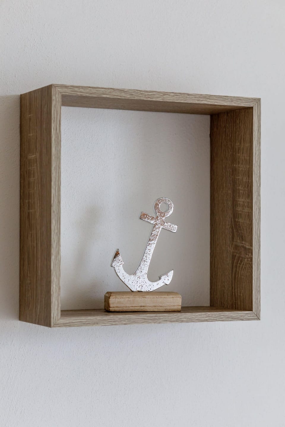 A small decorative anchor displayed on a wooden shelf, adding a nautical theme to the room.
