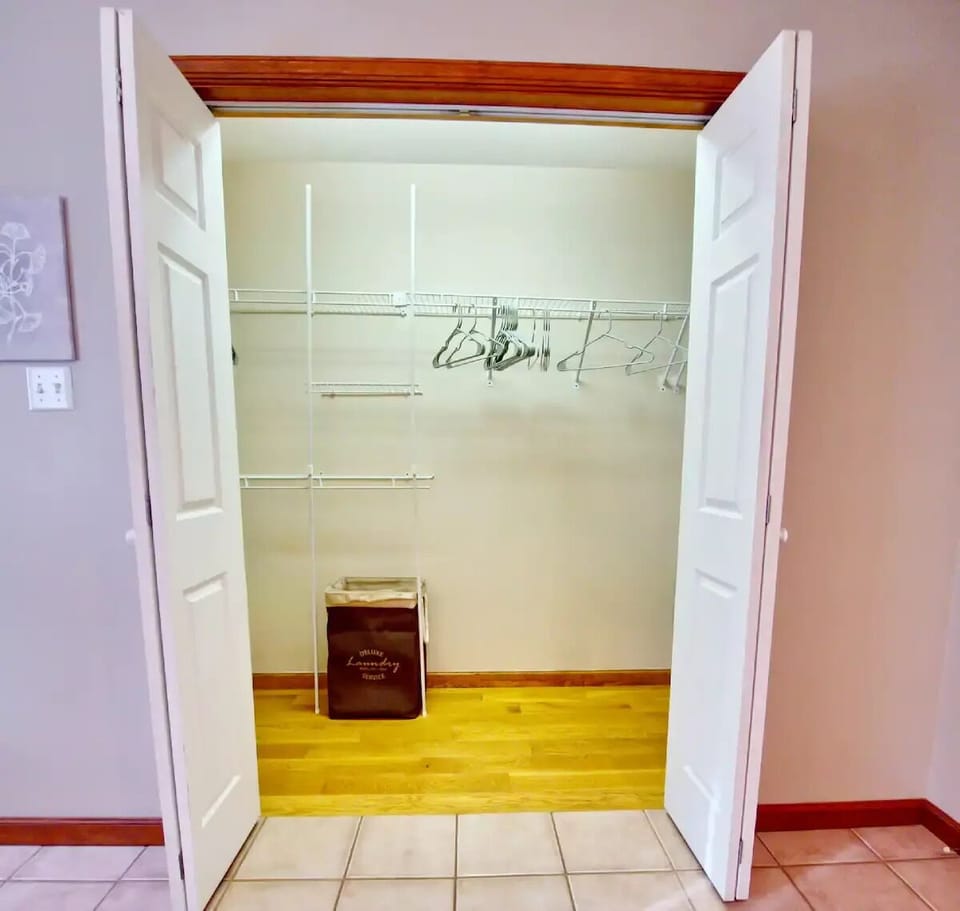 Large walk-in closet in master bath w/ hangers, a hamper, and space for luggage.